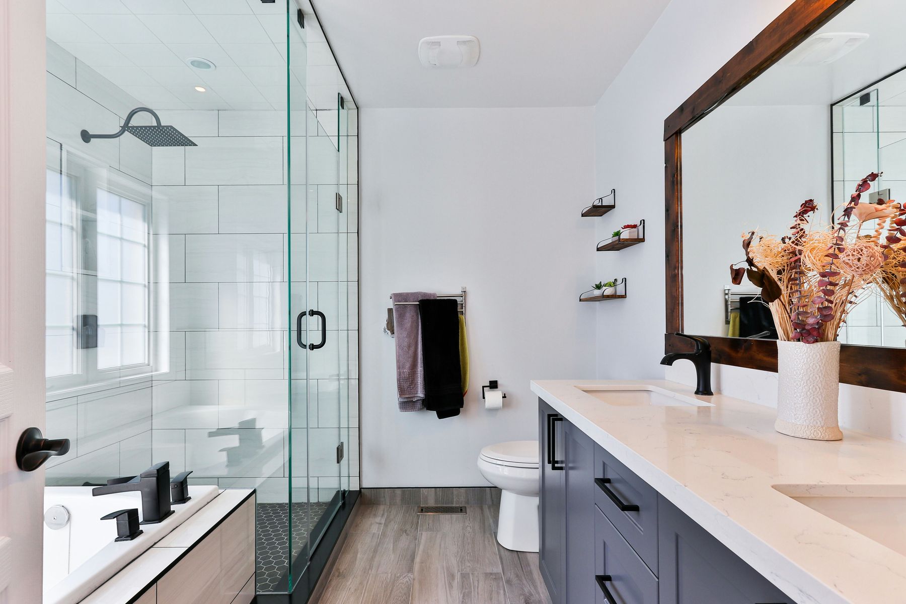 Walk-in shower with matte black fixtures and wood-framed mirror — The Ashford Project, Colleyville